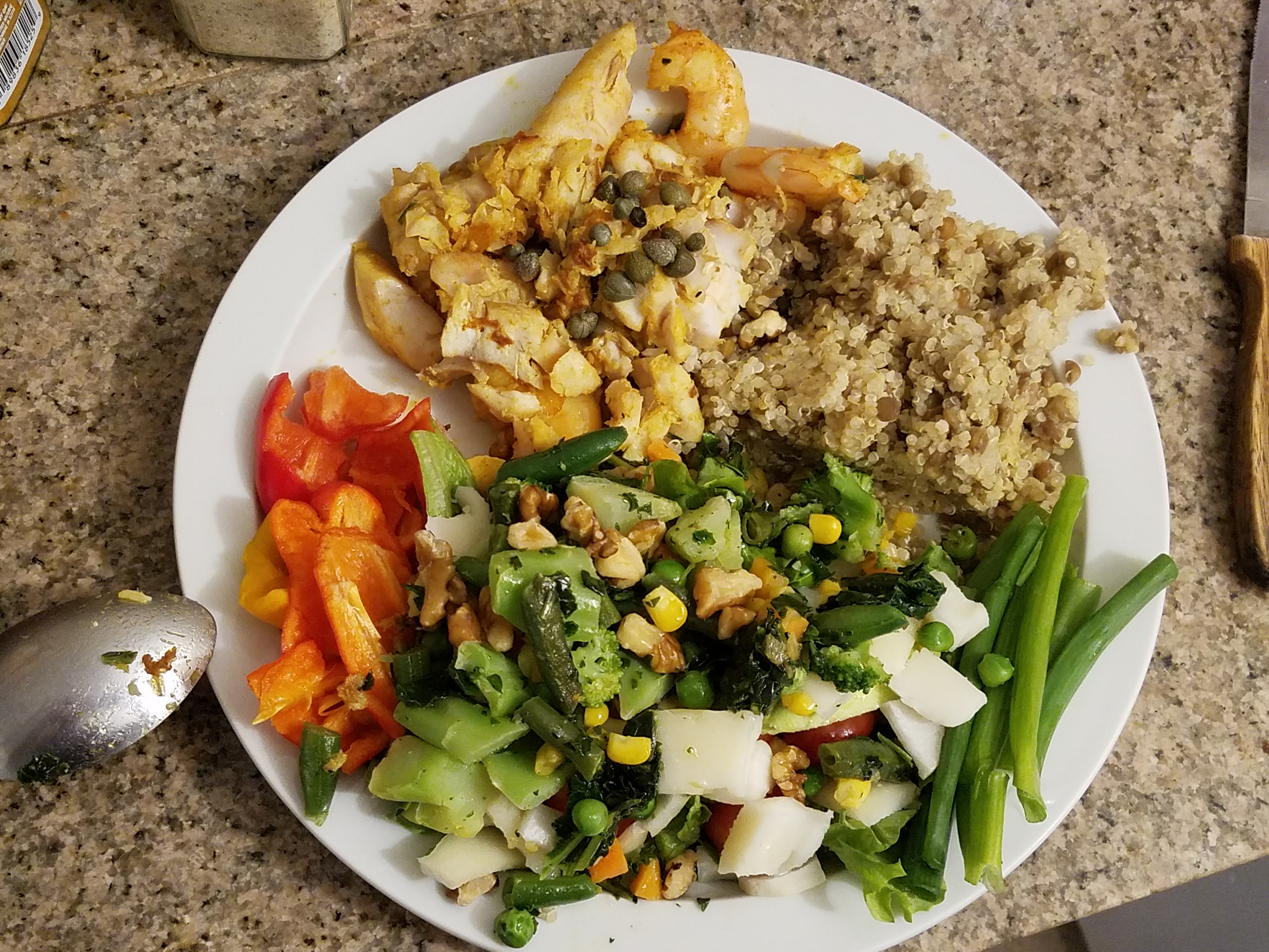 Living well in the 21st century. Limassol, Cyprus. A white plate with veggies - red pepper, cheese, green onions, celery, corn, quinoa, and fish. 