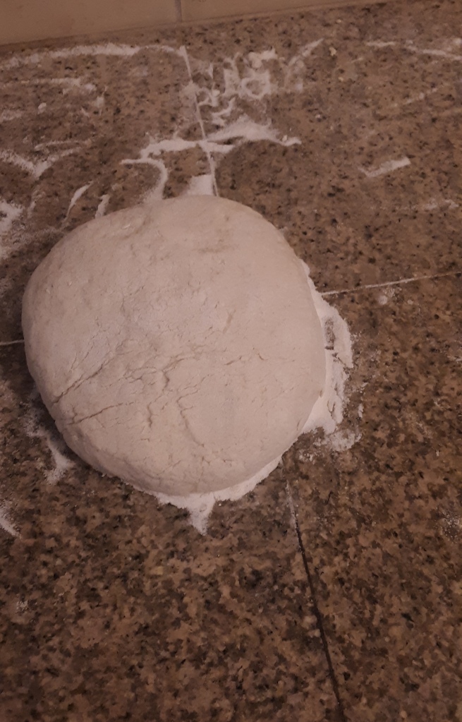 Living well in the 21st century - Limassol, Cyprus - a gluten free dough on a brown kitchen counter with flour in the background. 