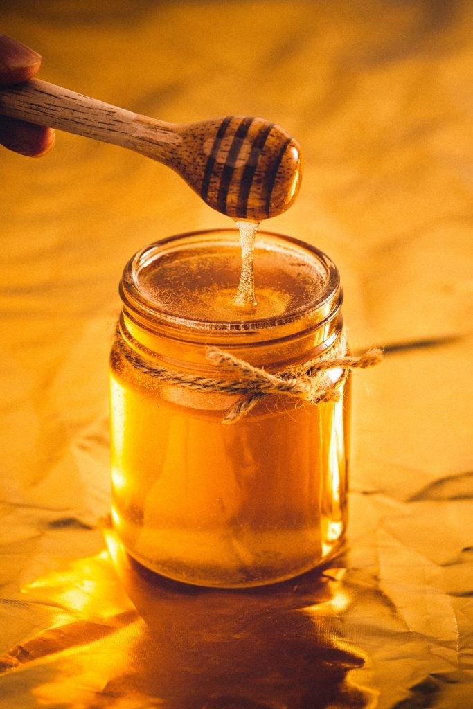 Living well in the 21st century - A container with honey, and a stick dripping with honey into the container. 